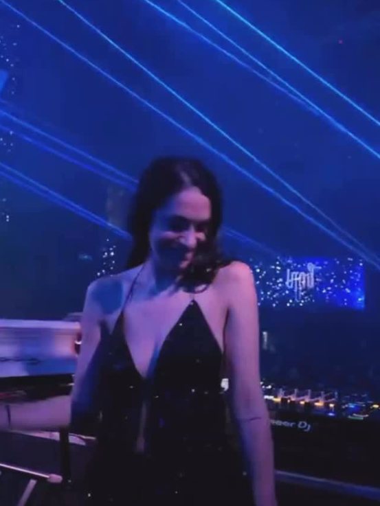 Sole in a sequin dress under blue lasers in the DJ booth