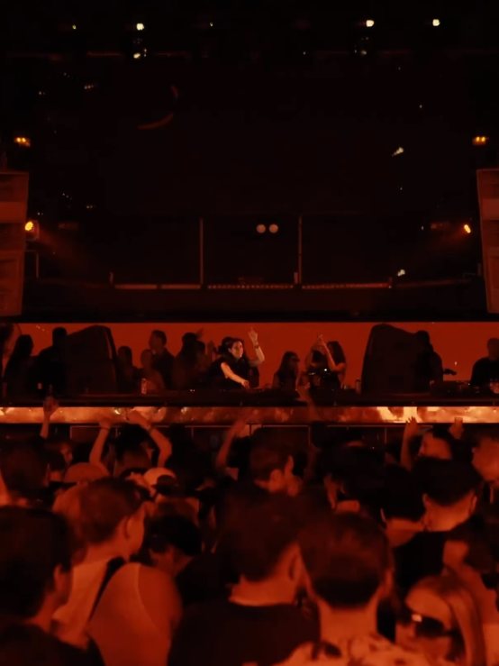 A packed club seen from the back, Sole in the booth under red light