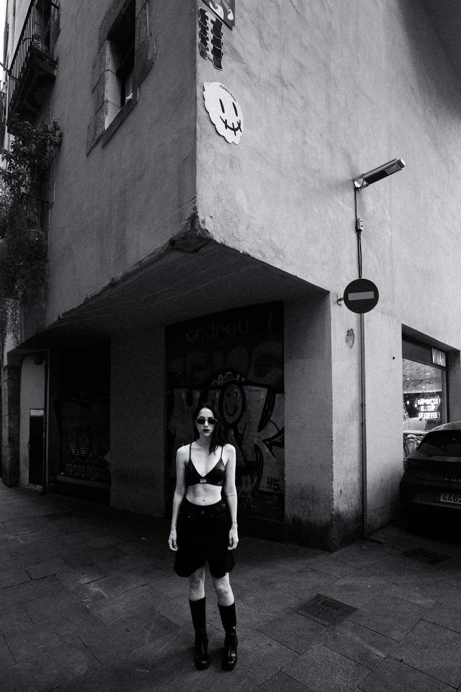 Black and white, standing at a street corner under a no-entry sign