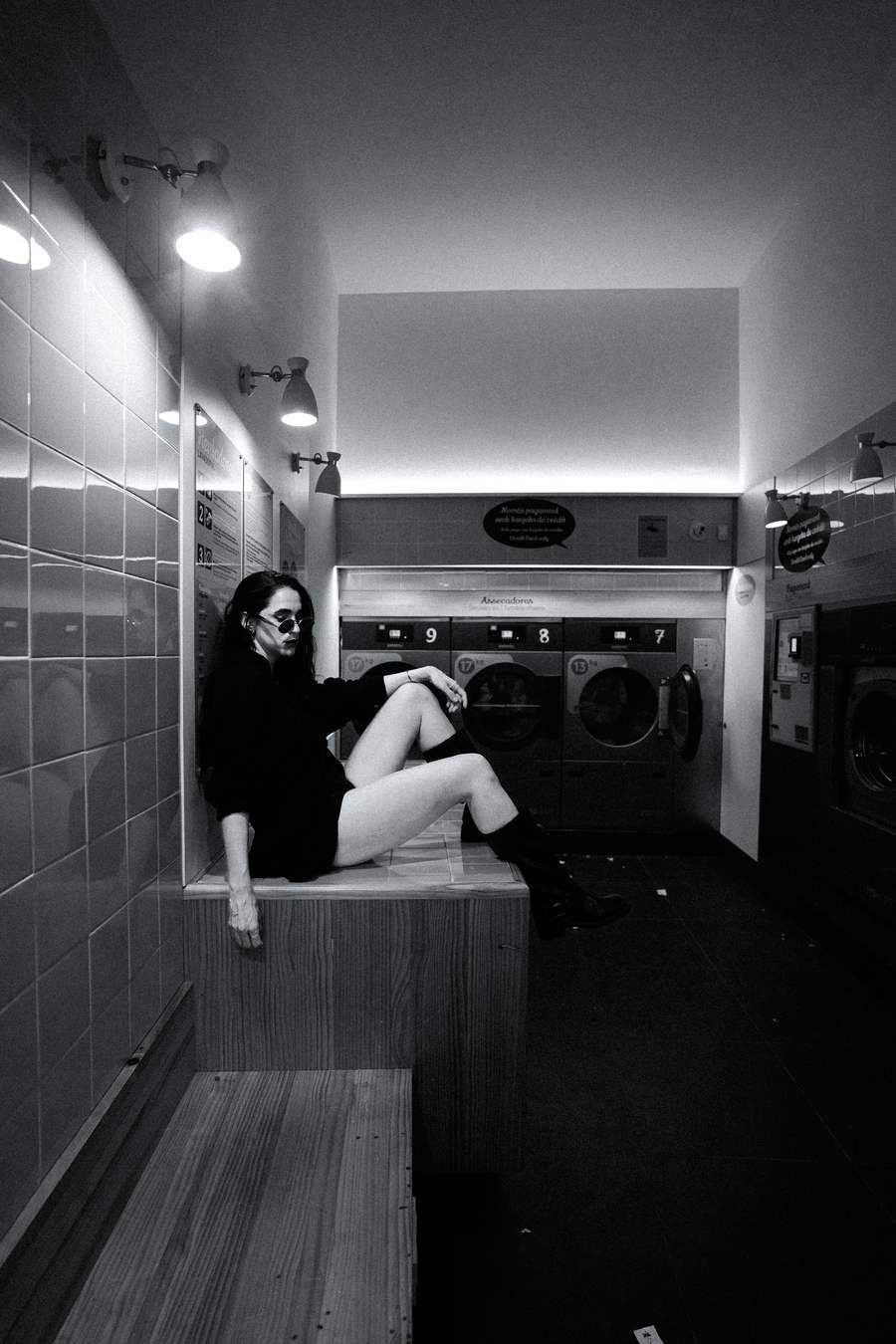 Black and white, seated on a bench in a laundromat