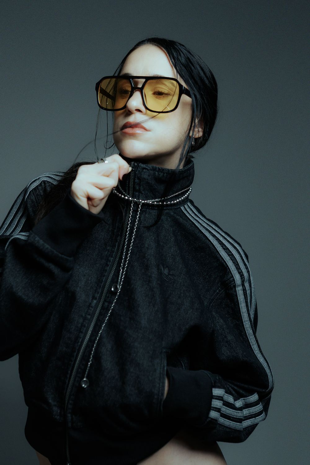 Yellow-tinted glasses and a black track jacket, close up