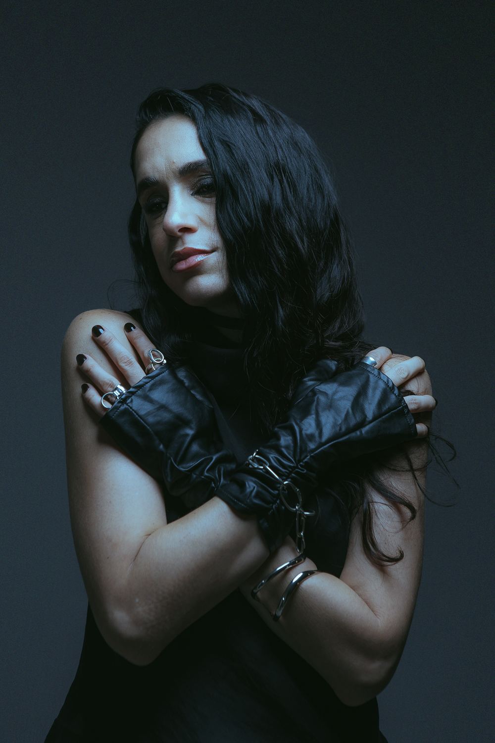 Close up in leather gloves, arms crossed over her shoulders